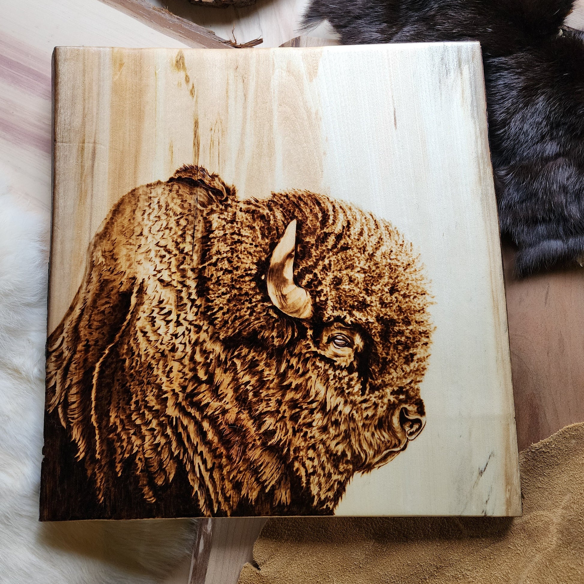 Wooden plaque with a pyrography design of a bear on a wooden surface.
